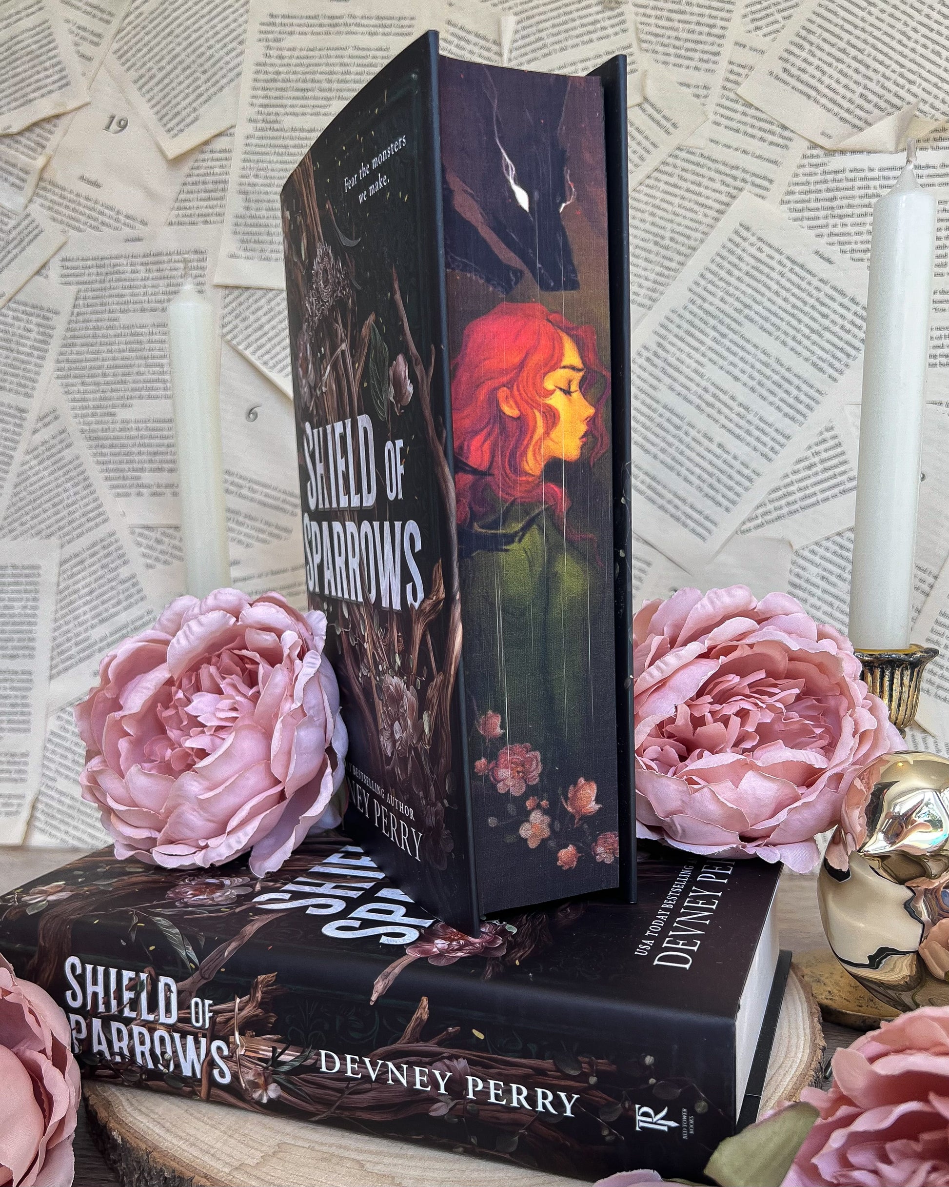 Book titled 'Shield of Parrows' by Devney Perry with pink roses and a candle on a textured surface.