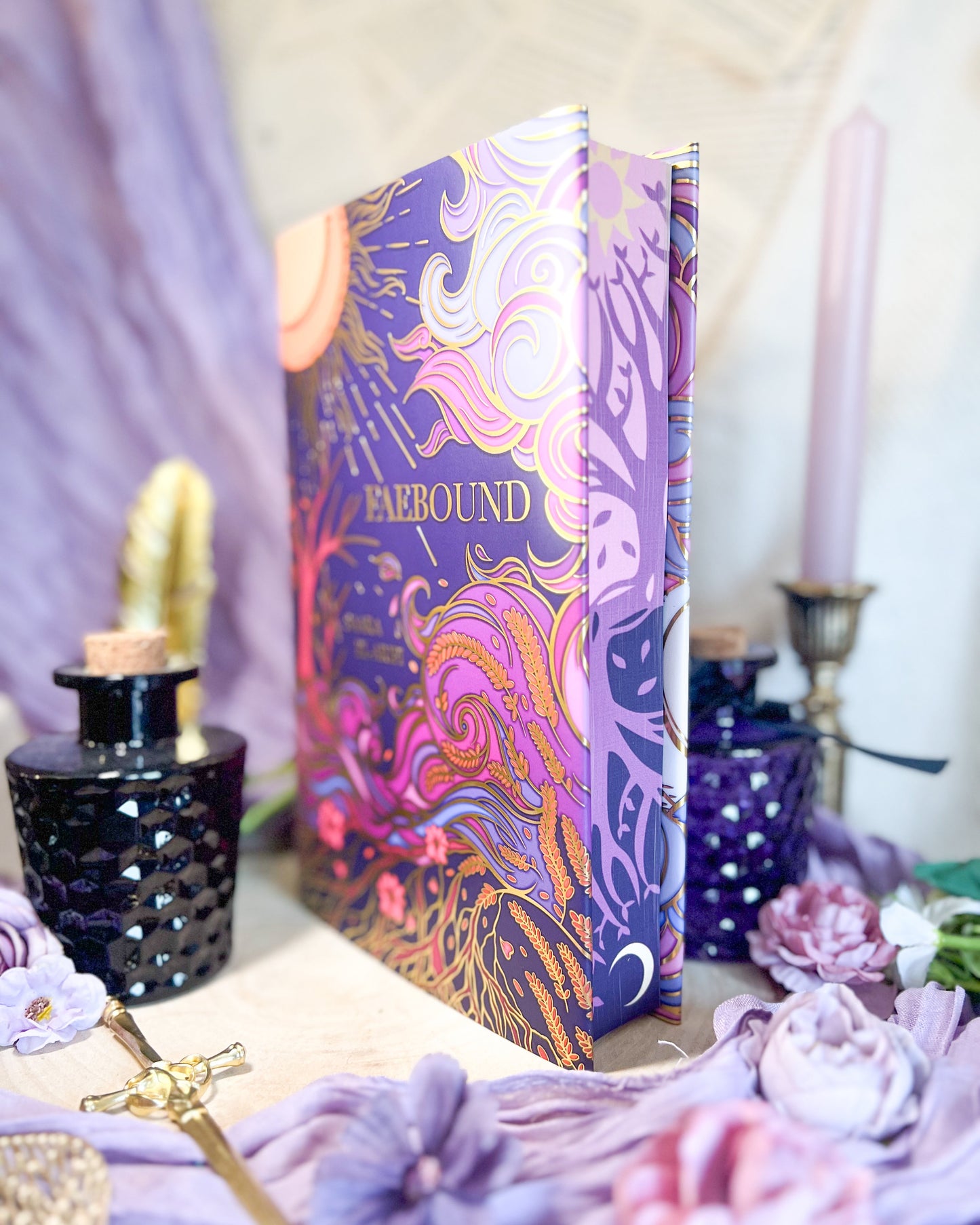 Colorful book with decorative elements on a table with flowers and candles.