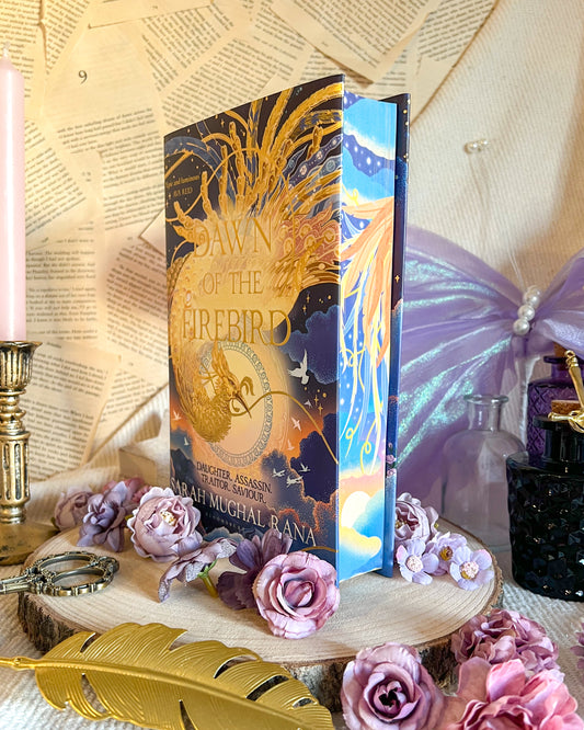 Decorative book with feather design on a table with flowers and candles