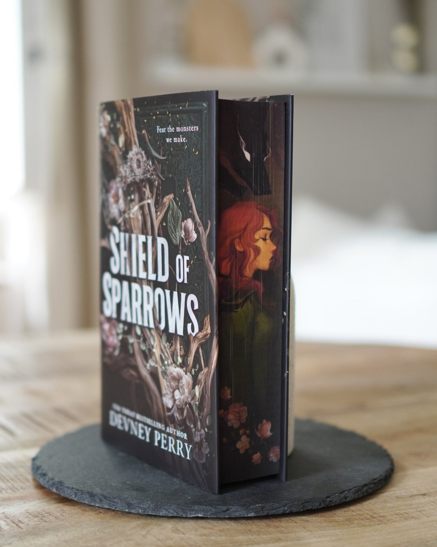 Book titled 'Shield of Sparrows' by Devney Perry on a stand with a blurred background